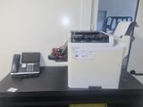 a printer sitting on top of a desk next to a phone