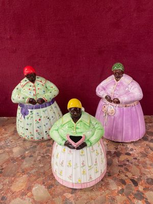 three figurines of women in colorful dresses sitting on a table