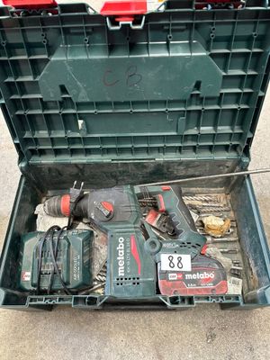 une boîte à outils verte posée par terre, contenant des outils