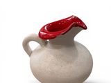 a white vase with a red handle on a white surface
