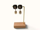 a pair of black and gold chandelier earrings on a wooden stand