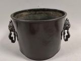 a black pot with two handles on a white surface