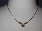 gold plated necklace with a blue crystal stone on a mannequin neck