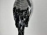 photographie en noir et blanc d'une sculpture représentant une tête d'homme sur un mur