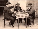trois hommes assis à une table en train de jouer à un jeu
