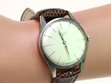 une personne tient une montre à son poignet, sur un fond blanc
