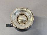 a close up of a silver cup with a handle on a table