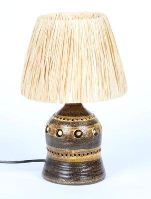 une petite lampe surmontée d'un abat-jour en paille