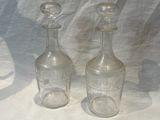 two empty glass bottles sitting next to each other on a table