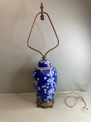 une image représentant un vase bleu et blanc sur lequel est posée une lampe