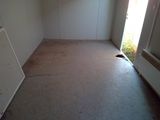a picture of a empty room with a refrigerator and a window