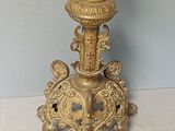 a gold candle holder with a candle on top of it