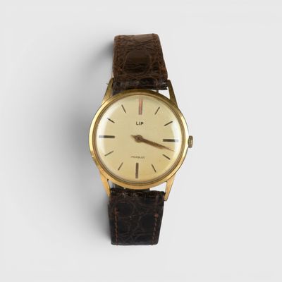 gros plan d'une montre sur une surface blanche avec un bracelet marron
