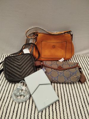 three purses and a wallet sitting on a bed with a striped blanket