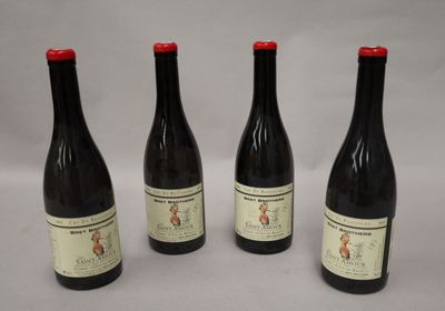 quatre bouteilles de vin sont alignées sur une surface blanche