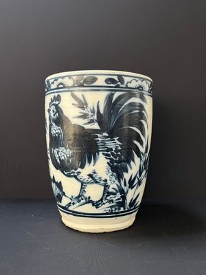 un vase bleu et blanc orné d'un coq, posé sur une table
