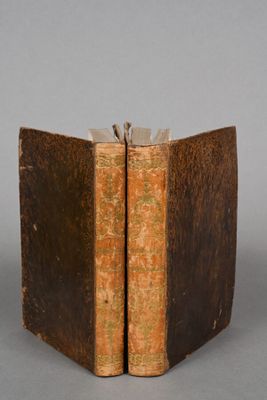 two old books sitting on top of each other on a table