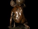 bronze statue of a baby sitting on top of a wooden table