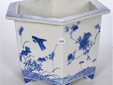 a blue and white planter with birds and flowers on it