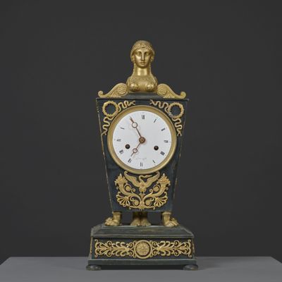 une horloge sur laquelle trône une statue, posée sur une table