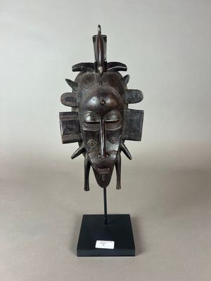 un gros plan d'une sculpture métallique représentant un visage, posée sur un socle