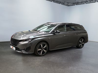 La voiture grise est garée dans une grande pièce aux murs blancs.