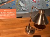 a lamp that is sitting on a table in front of a climbing wall