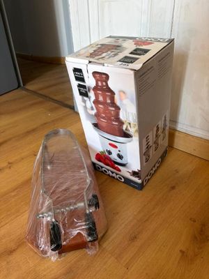 une fontaine à chocolat posée par terre à côté d'un sac en plastique