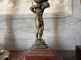 a bronze statue of a boy holding a globe on his head