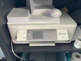 une imprimante posée sur une étagère, à côté d'un rouleau de papier toilette