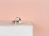 un gros plan d'une bague en perle et argent posée sur un bloc de marbre
