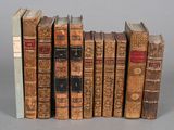 several old books are lined up in a row on a gray surface