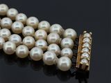 collier de perles avec un fermoir en or sur un fond noir