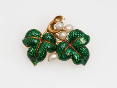 une photo en gros plan d'une broche ornée de feuilles et de perles