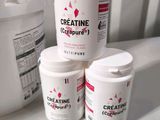 three buckets of creatine sitting on a counter next to a container of creatine