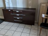 un sol carrelé dans une pièce où se trouvent une commode et une chaise
