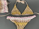 two pieces of swimwear with a drawstring bag on a gray surface