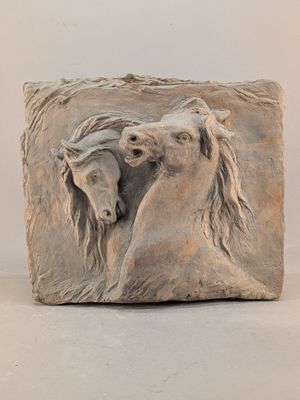 sculpture représentant deux chevaux sur un bloc de pierre, sur fond blanc