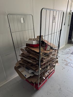 un chariot rempli de cartons et des cartons par terre dans une pièce