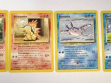 four pokemon cards are lined up on a white surface