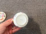 a person holding a cup on the floor next to a coaster