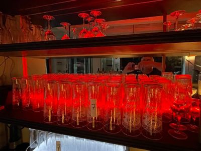 many glasses on a shelf with red lights