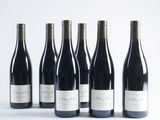 six bottles of wine are lined up on a white surface