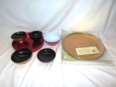 une assiette, des bols, des tasses et des soucoupes posés sur un lit