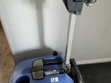 a blue and black vacuum on the floor next to a wall