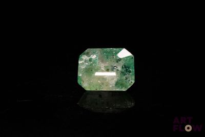 un gros plan d'une émeraude verte sur une surface noire