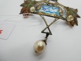 une photo d'une broche à laquelle est suspendue une perle