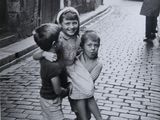photographie en noir et blanc d'un groupe d'enfants jouant dans une rue pavée