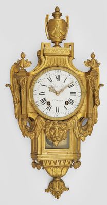 a gold clock on the wall with roman numerals on it