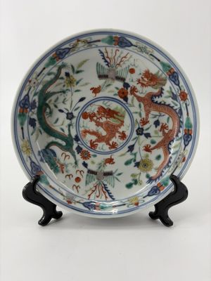une image représentant une assiette ornée d'un dragon, posée sur un socle